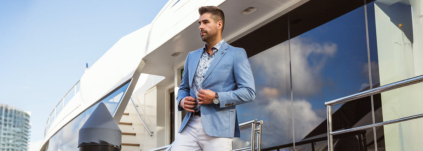 un homme habillé à la mode fashion portant un veston bleu et une chemise blanche à pois
