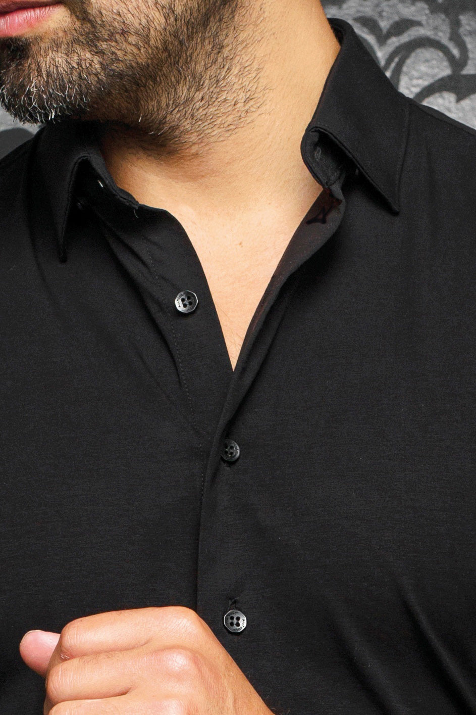 Gros plan de chemise noire montrant le col classique, la patte boutonnée et les boutons noirs pour homme par Au Noir