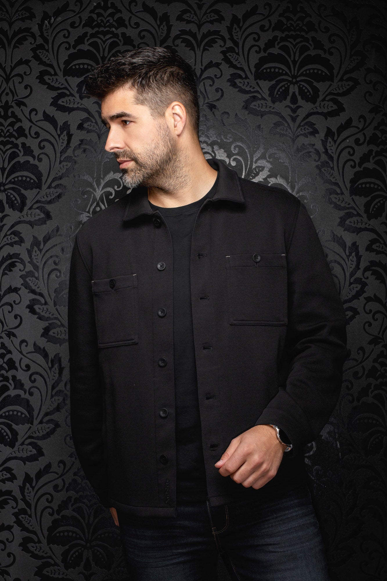 Surchemise noire sur mannequin, vue de face avec col, patte boutonnée et poches poitrine pour homme par Au Noir