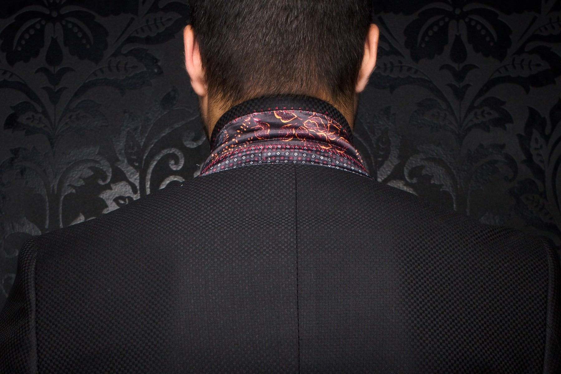 Men's back close-up of a black textured blazer with patterned collar lining and center back seam by Au Noir