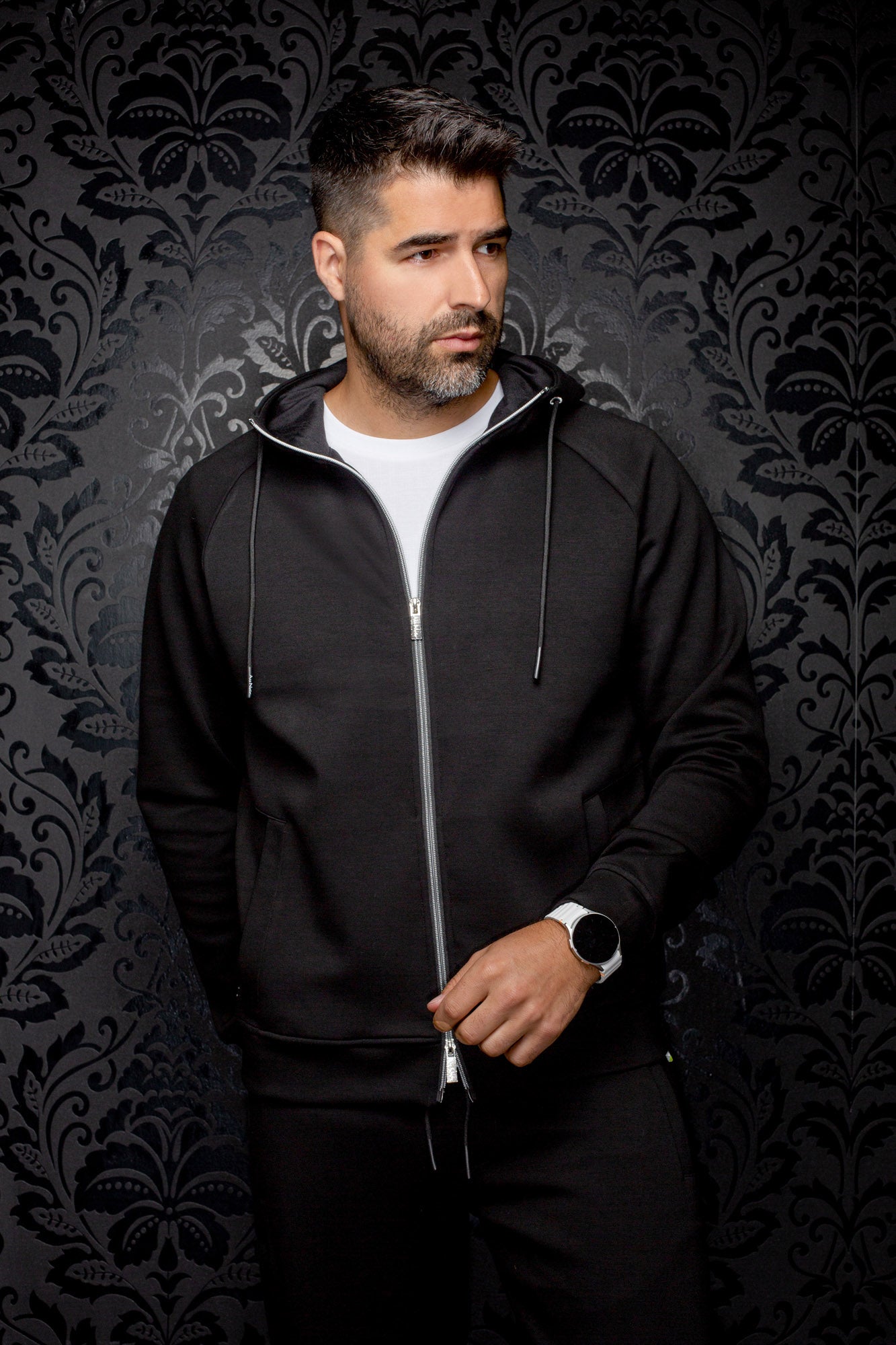 Veste sport noire à capuchon, glissière argentée et poches pour homme par Au Noir, vue de face sur mannequin