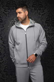 Veste sport à capuchon gris pâle vu de face, avec glissière noire, cordons et poches pour homme par Au Noir