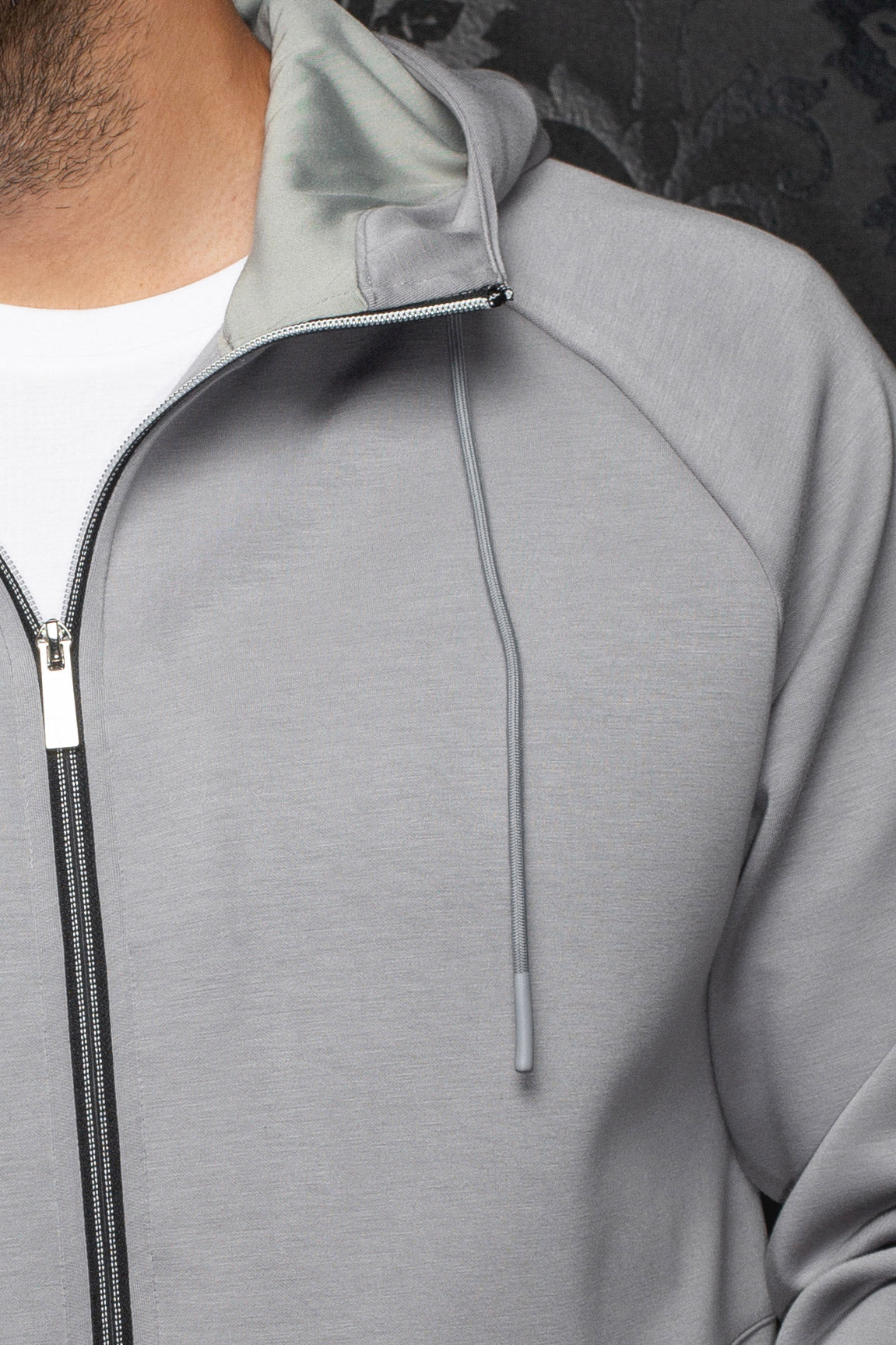 Veste sport à capuchon gris pâle avec doublure, glissière noire et cordon pour homme par Au Noir, en gros plan