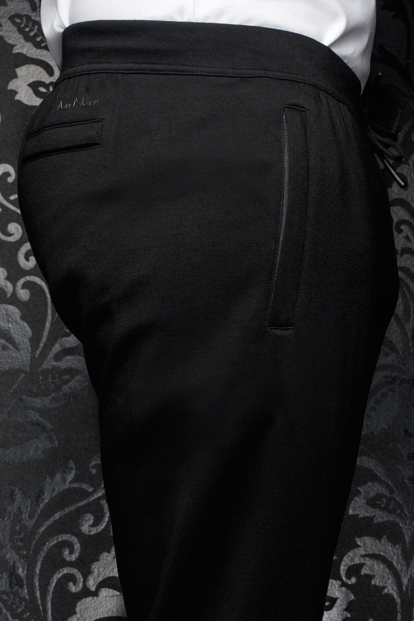 Pantalon jogging noir avec taille large, poche passepoilée et logo ton sur ton pour homme par Au Noir, en gros plan