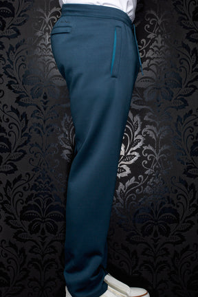 Men's side-back view of teal jogging pants with drawcord waistband and vertical zip pocket by Au Noir