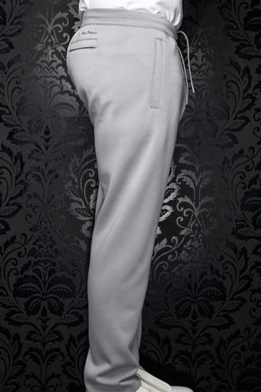 Men's light gray jogging pants side view with elastic waistband, drawcord, welt pockets, and full leg by Au Noir