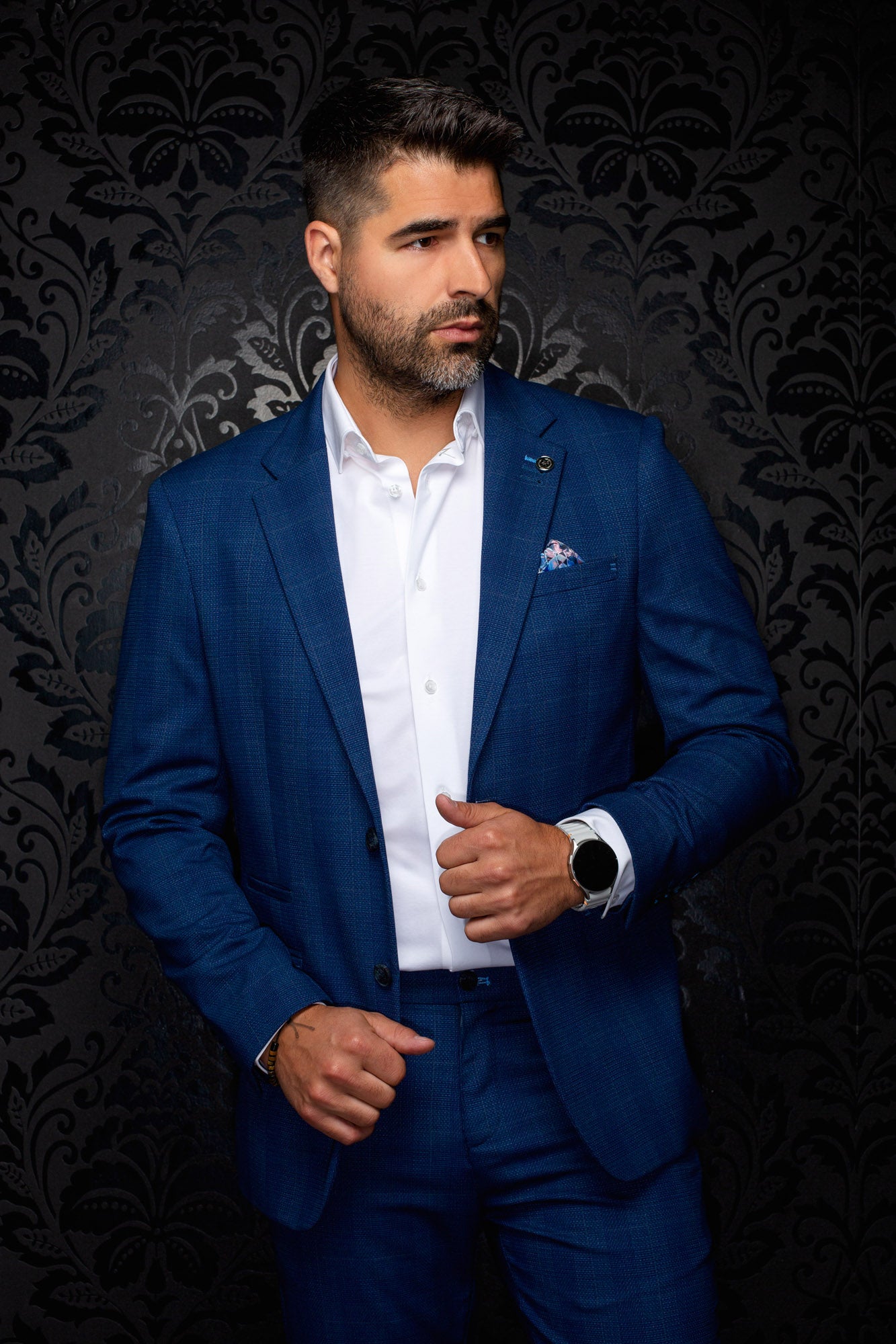 Veston bleu texturé avec revers crantés, poches à rabat et épinglette pour homme par Au Noir, vue de face sur mannequin