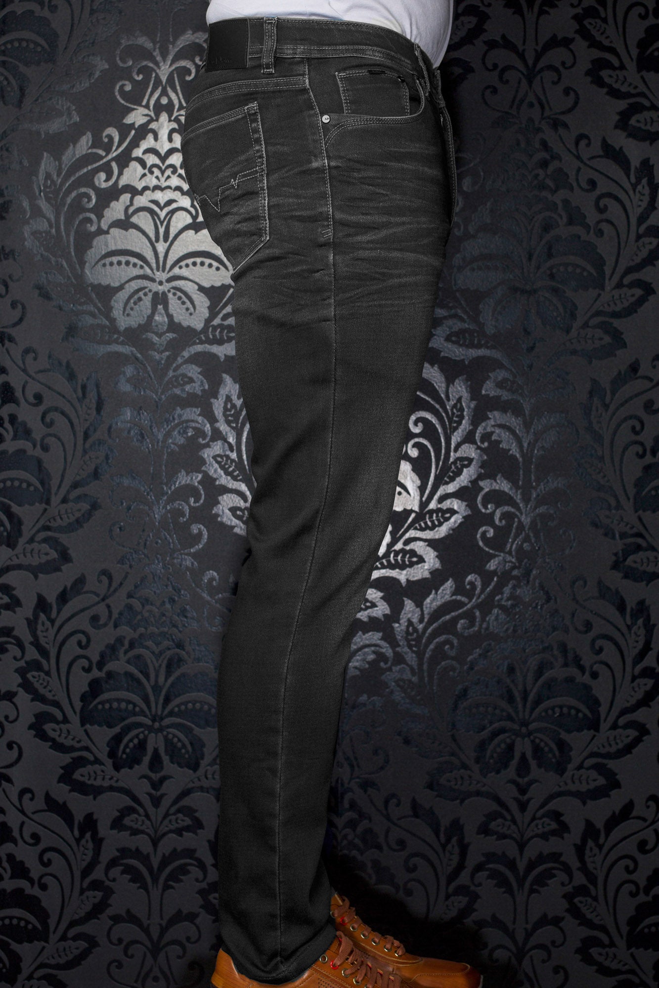 Jean noir vu de côté, avec surpiqûres contrastantes, poche arrière et écusson à la taille pour homme par Au Noir