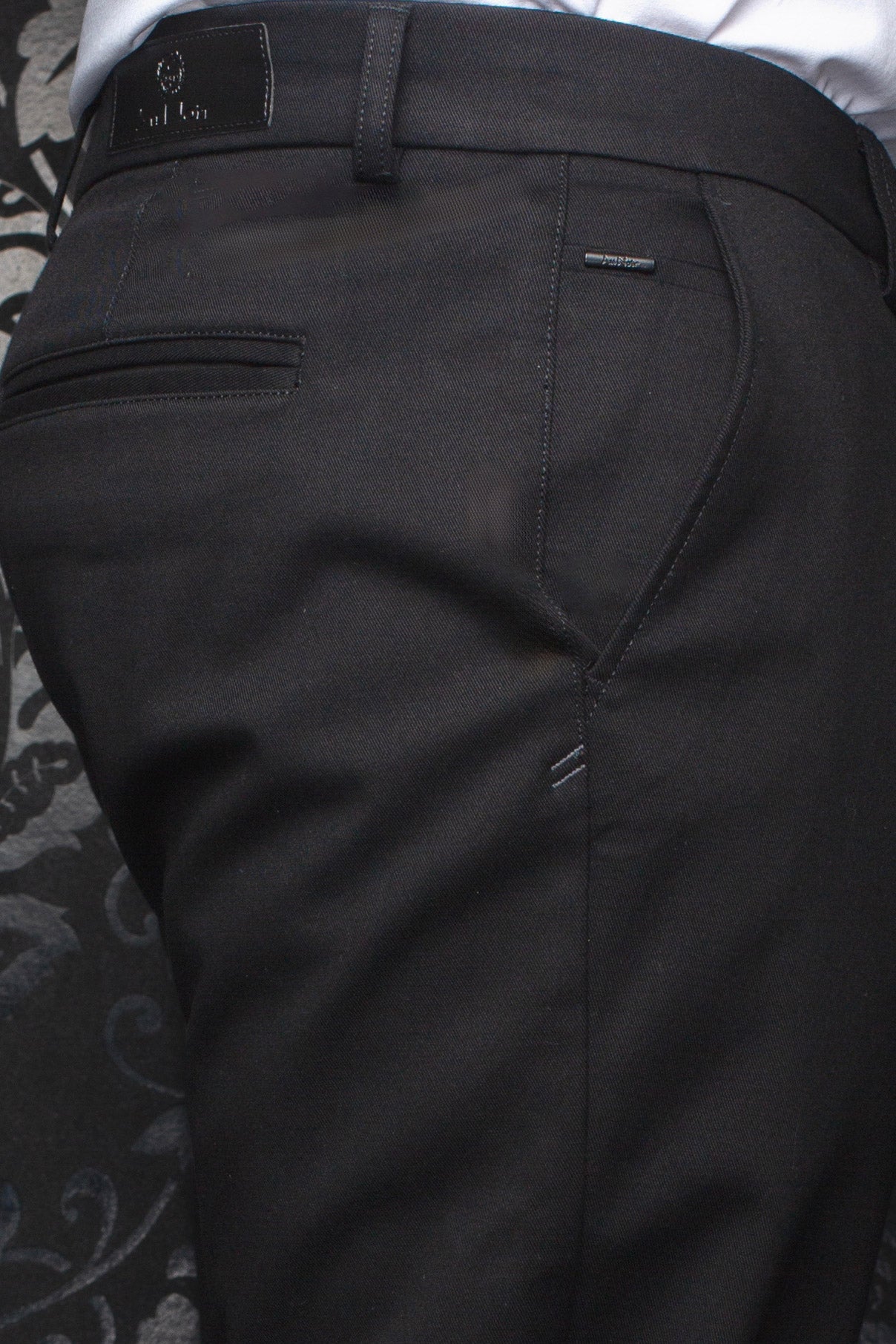 Pantalon chino noir montrant taille arrière, passant, poche passepoilée et logos pour homme par Au Noir, en gros plan