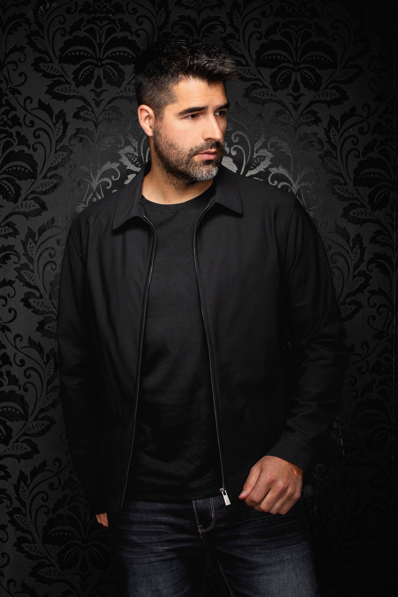Vue de face d’un coupe-vent mi-saison style bomber noire zippé porté ouvert avec col pointu pour homme par Au Noir