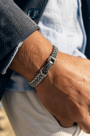 Bracelet argenté à maillons multiples porté au poignet, fermoir à logo visible pour homme par Au Noir, détail