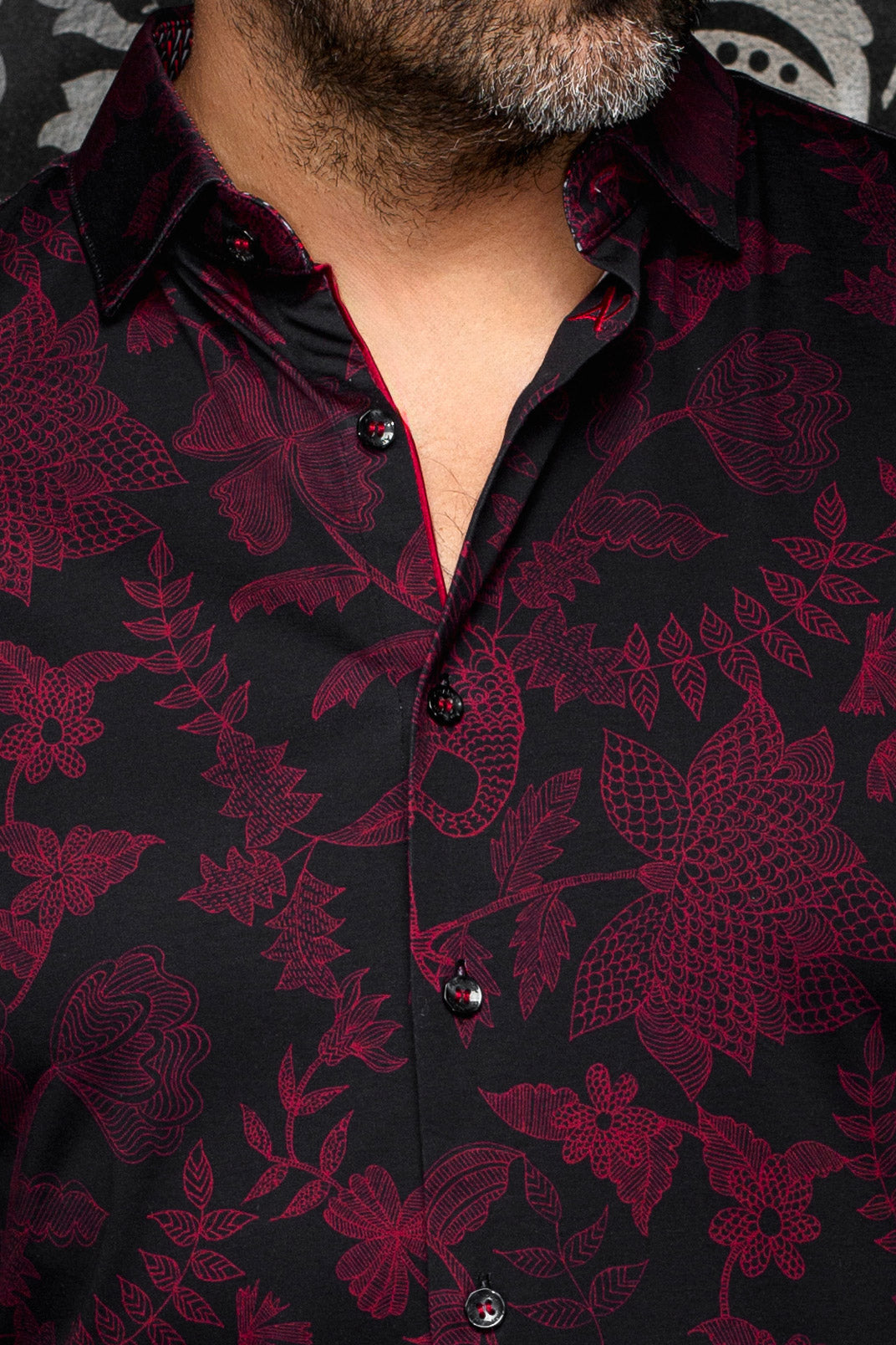 Au Noir men's black button-up shirt collar, burgundy floral print, glossy buttons and red trim, close-up