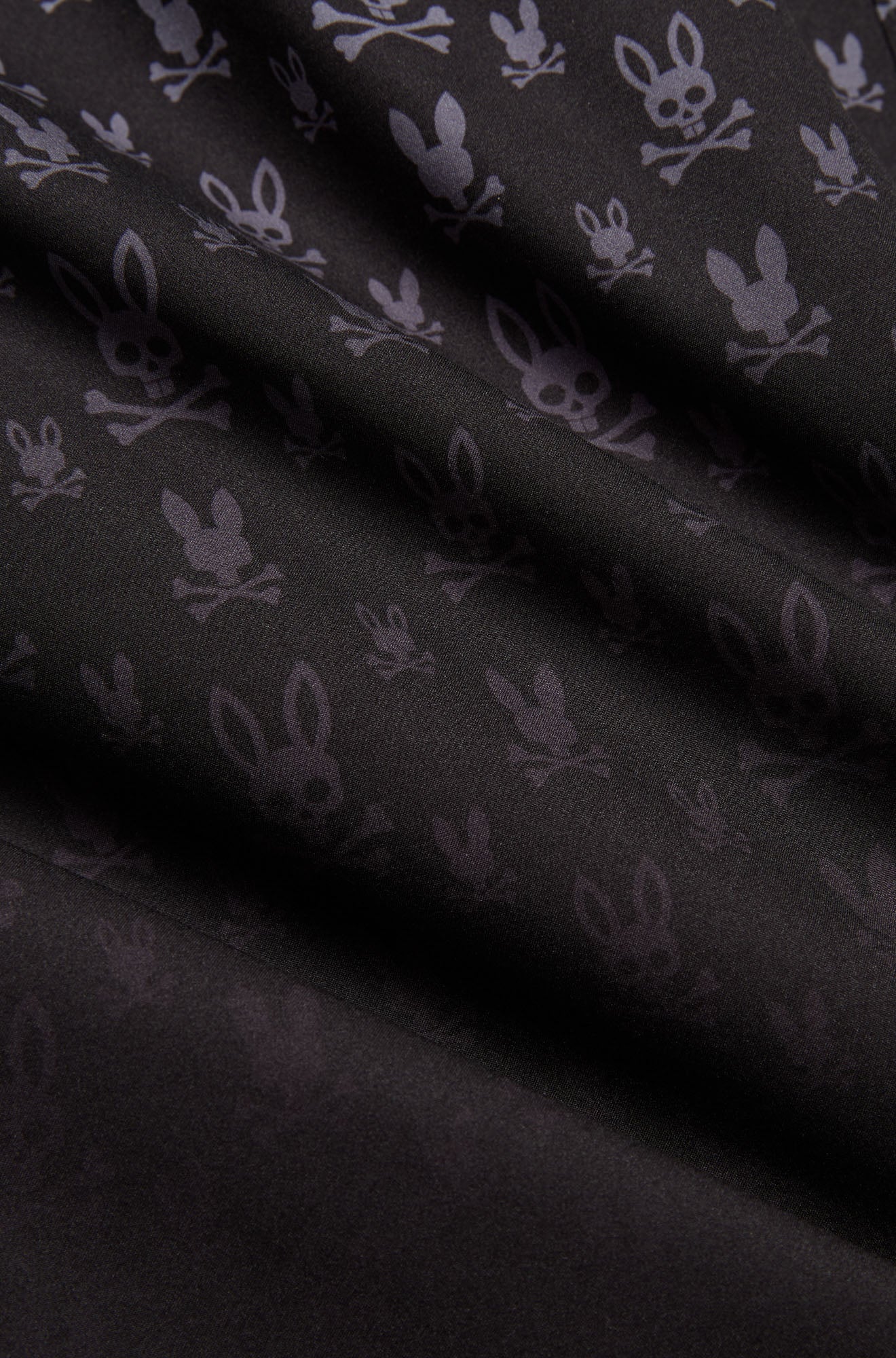 Gros plan du short maillot noir à motif lapin tête de mort gris foncé et texture tissée lisse pour homme par Psycho Bunny