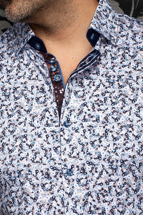 Col de chemise blanche à fleurs, boutons bleus et patte contrastée pour homme par Au Noir, en gros plan