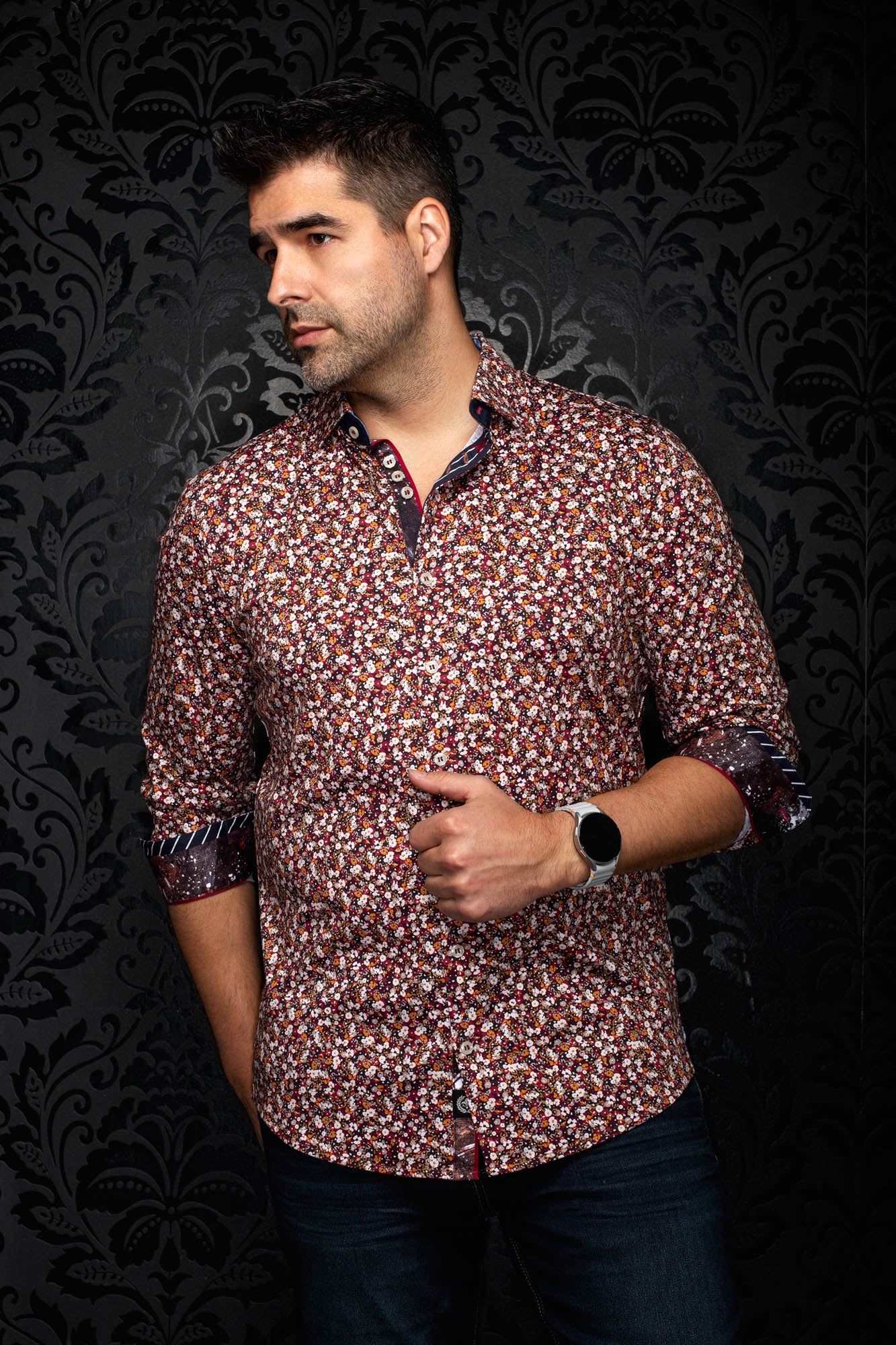 Men's angled front view of burgundy floral button-up shirt with rolled contrast cuffs and dark placket trim by Au Noir
