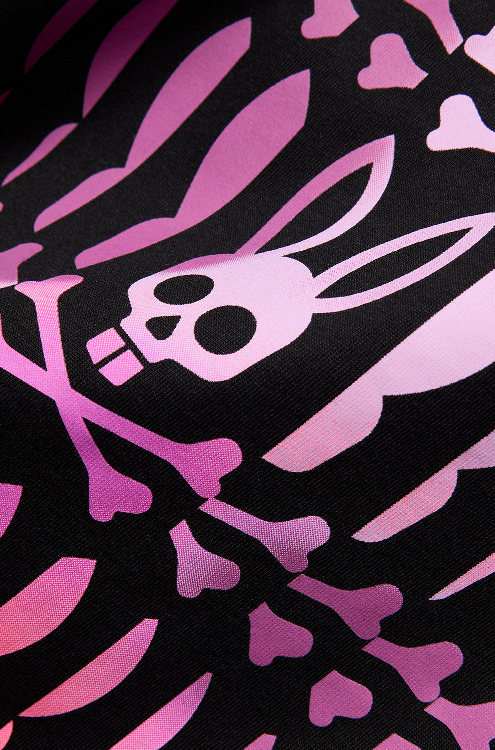 Gros plan du T-Shirt rose avec os sur le tissu noir du T-Shirt, crâne et graphique Psycho Bunny pour homme