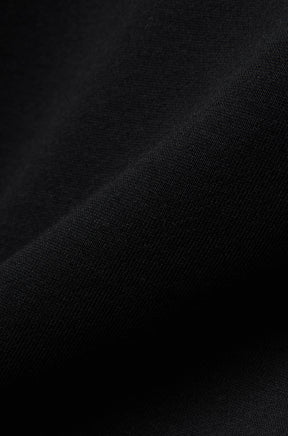 Gros plan du tissu en maille noire du chandail manches longues pour homme par Psycho Bunny