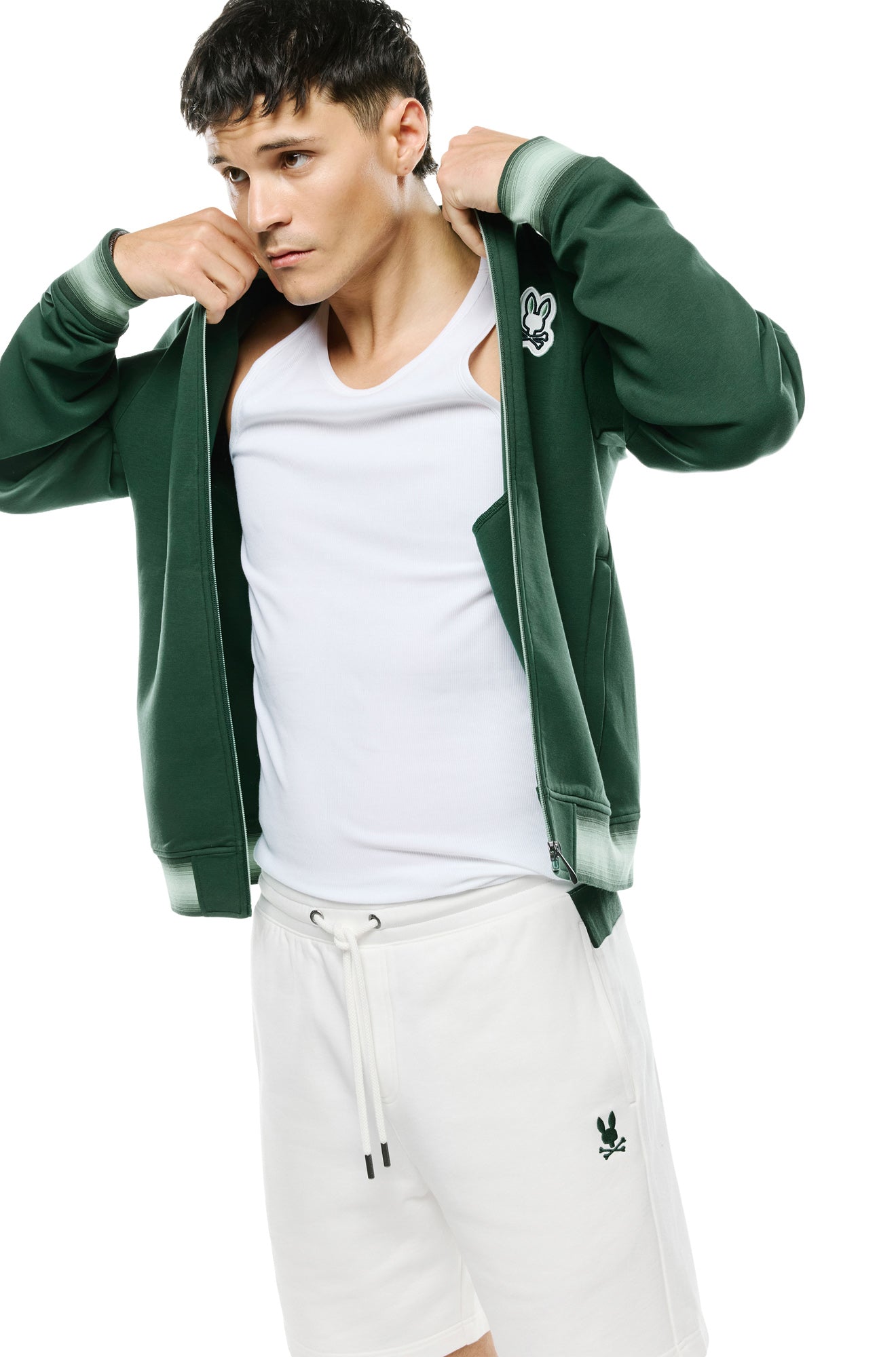 Vue en angle du jacket bomber verte ouverte montrant poignets rayés, poche et glissière pour homme par Psycho Bunny