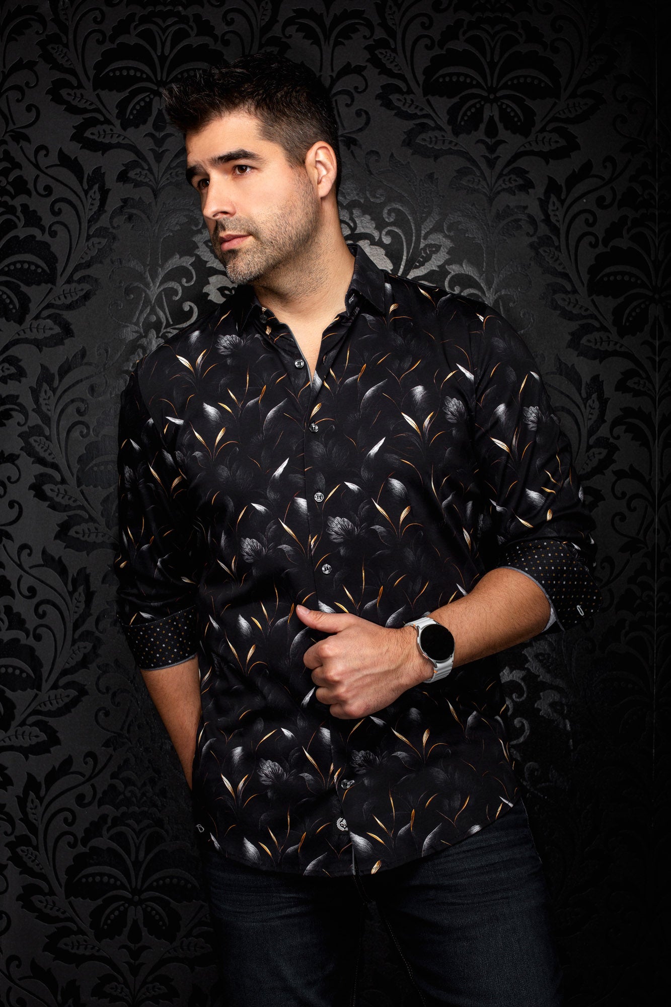 Vue en angle d’une chemise noire fleurie avec poignets roulés et accents de feuilles orange pour homme par Au Noir