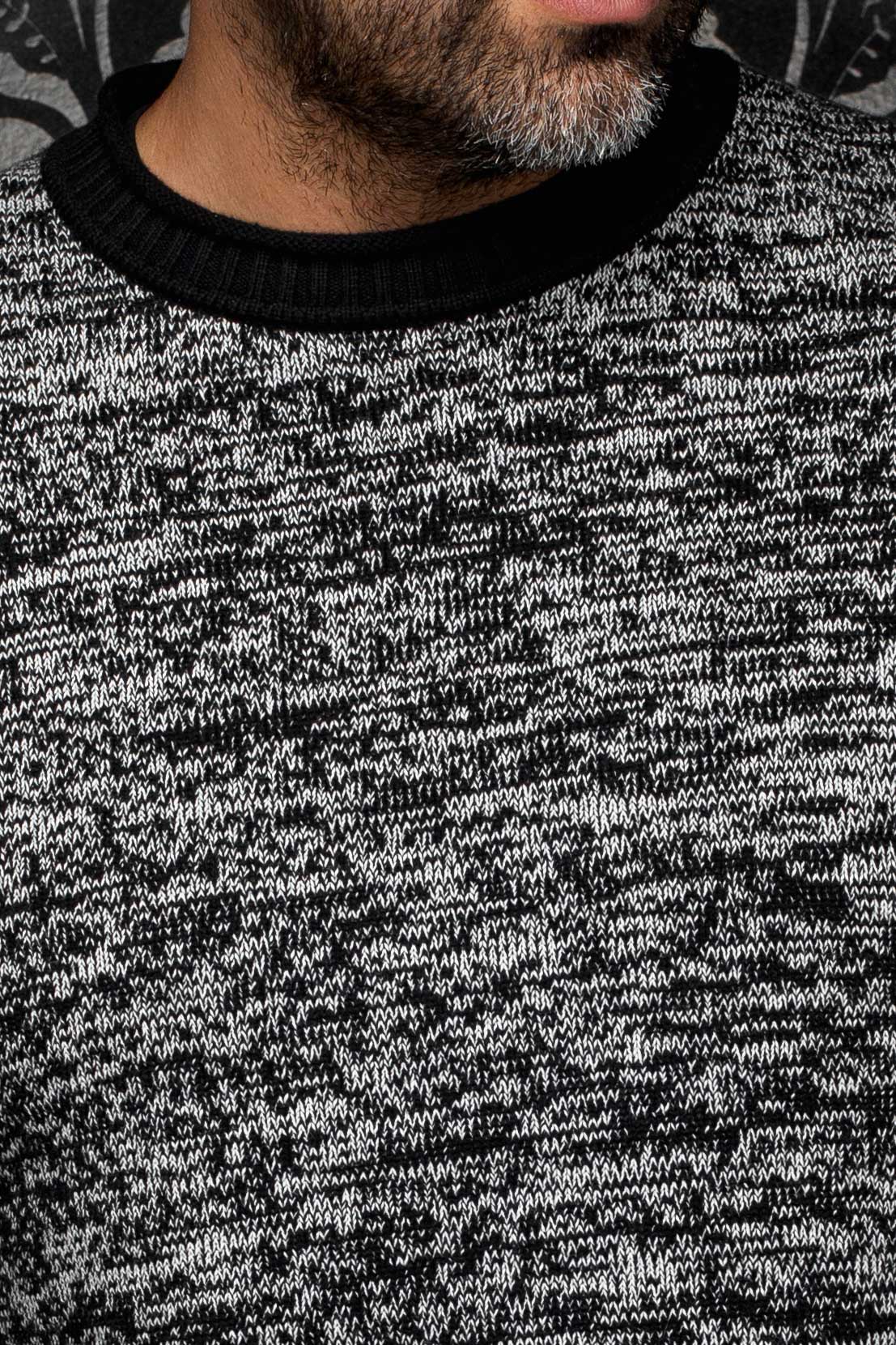 Gros plan de la chandail en cachemire en tricot gris chiné pour homme par Au Noir : le col rond côtelé noir et la maille