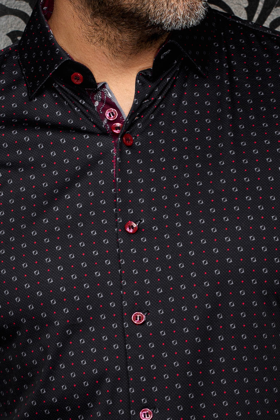 Gros plan d’une chemise noire à boutons rouges, motif géométrique fin et patte contrastante pour homme par Au Noir
