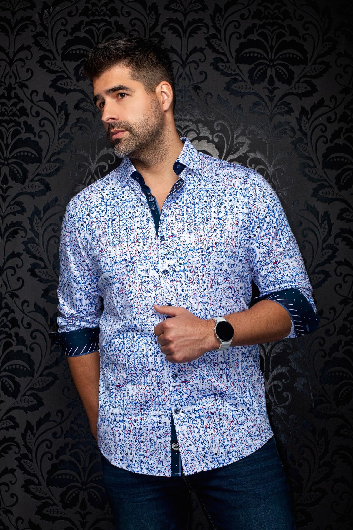 Au Noir men's angled model view of white floral button-up shirt with blue and red print and navy rolled cuffs, side view