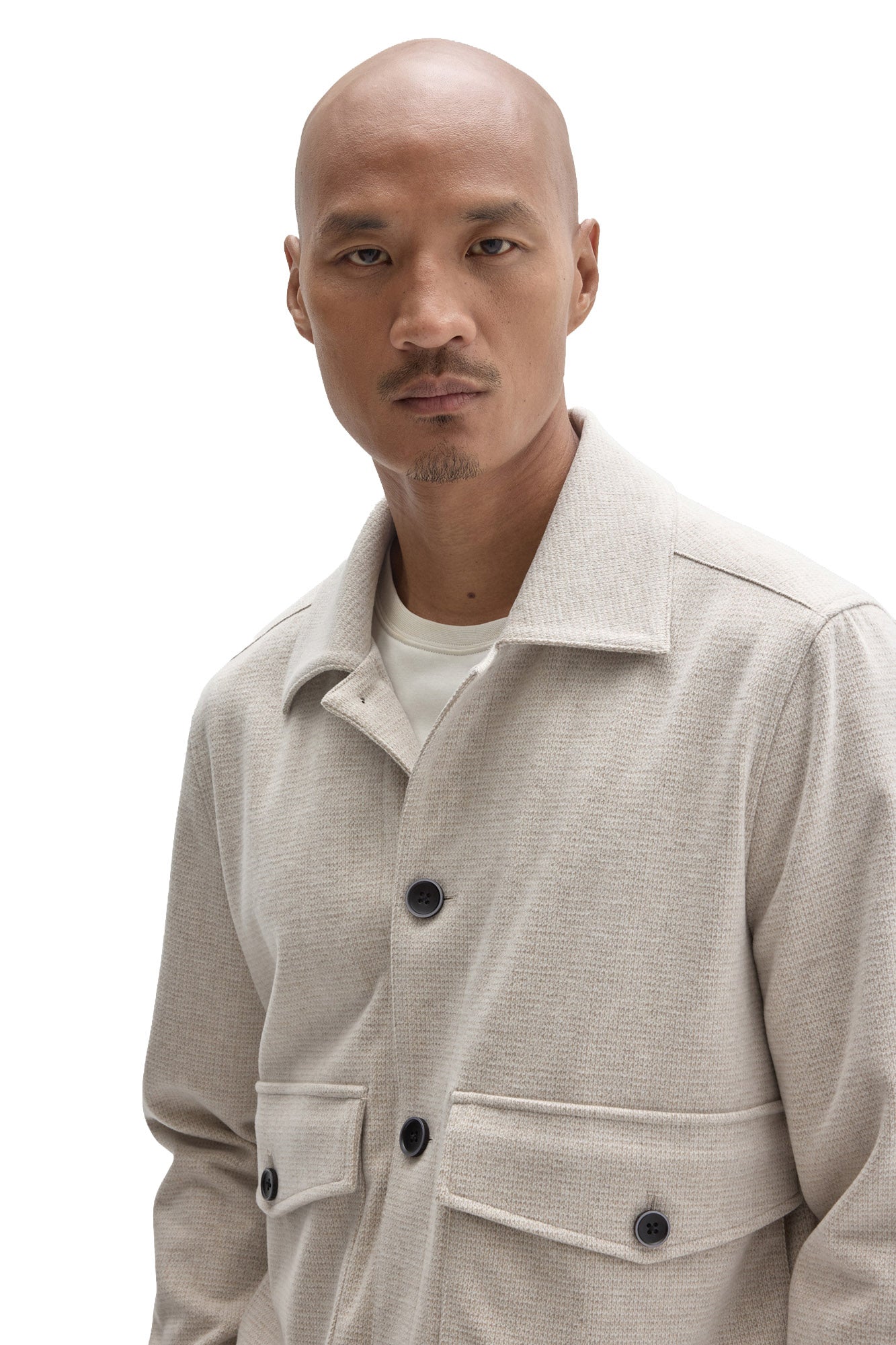 Close-up of men's cream textured jacket collar, flap pocket details and dark buttons by Robert Barakett