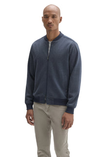 Men's front angled view of blue zip jacket with welt pockets, hem, cuffs and ribbed baseball collar by Robert Barakett