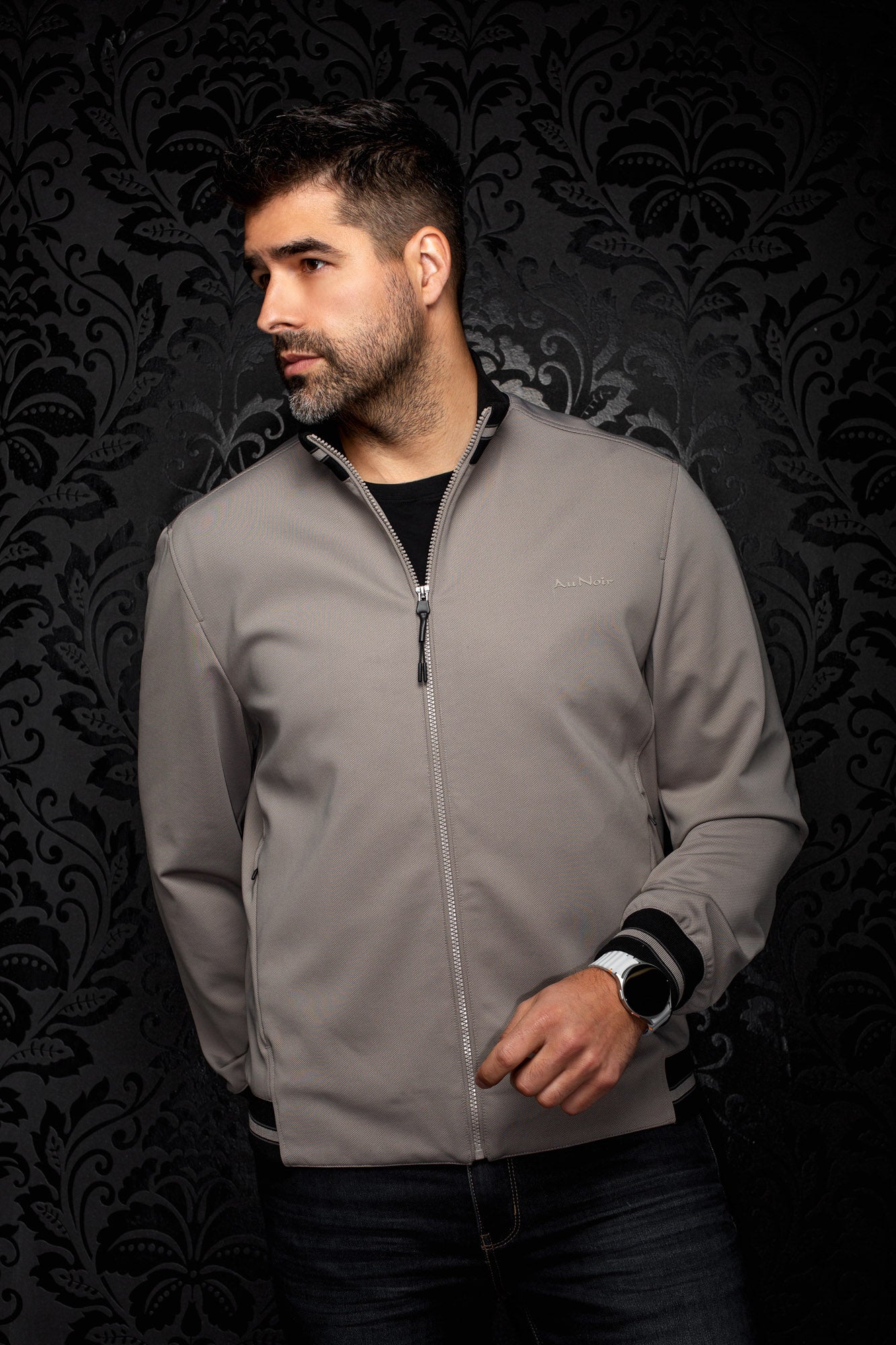 Coupe-vent mi-saison style bomber bomber grise zippé vue de face avec bordures côtelées noires pour homme par Au Noir