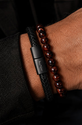 Bracelet noir tressé et brun rougeâtre à perles au poignet, fermoir logo avec bracelets pour homme par Au Noir, en gros plan