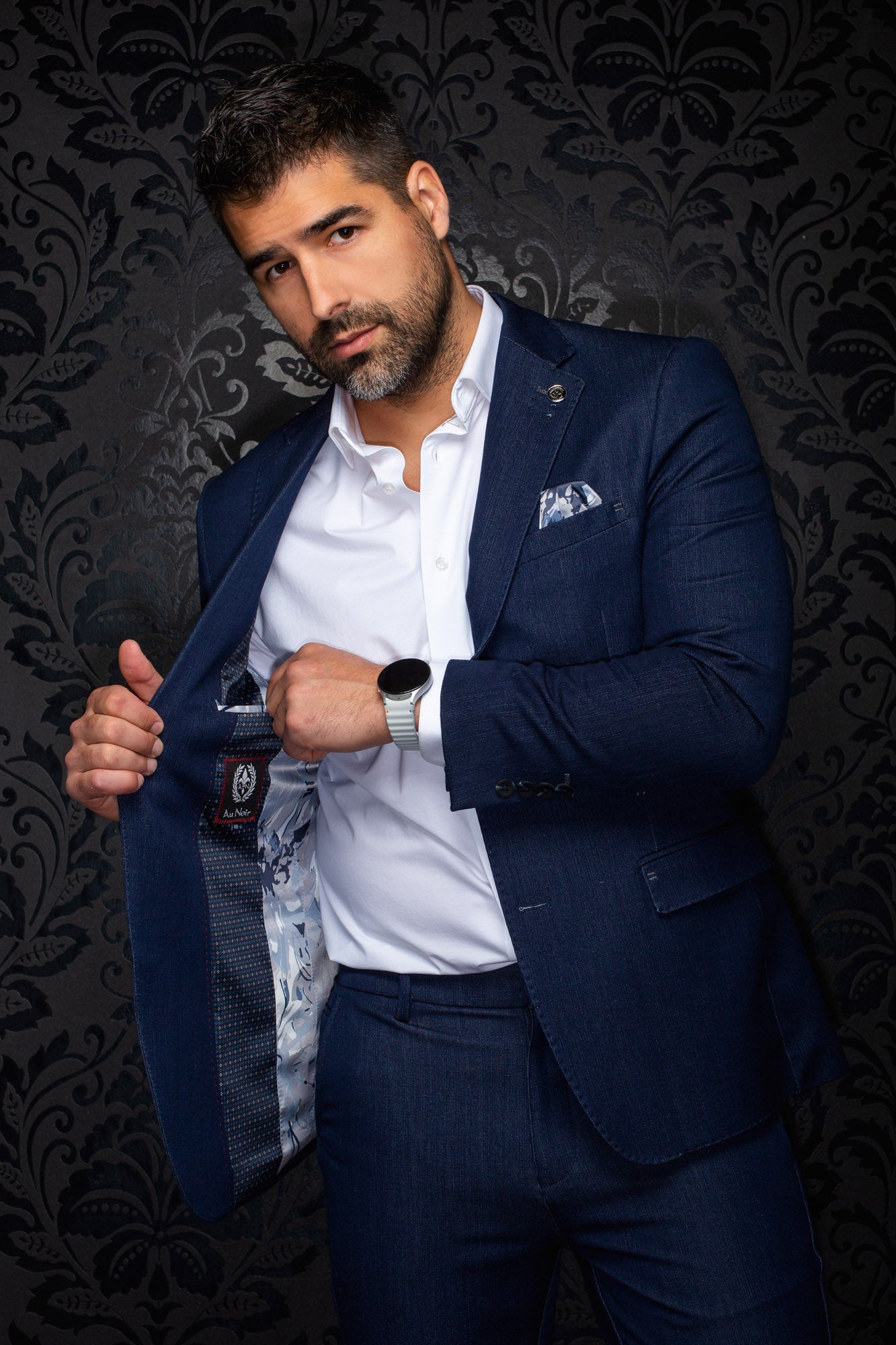 Au Noir men's navy blazer held open showing patterned lining, interior label, and lapel pin on a model, detail view
