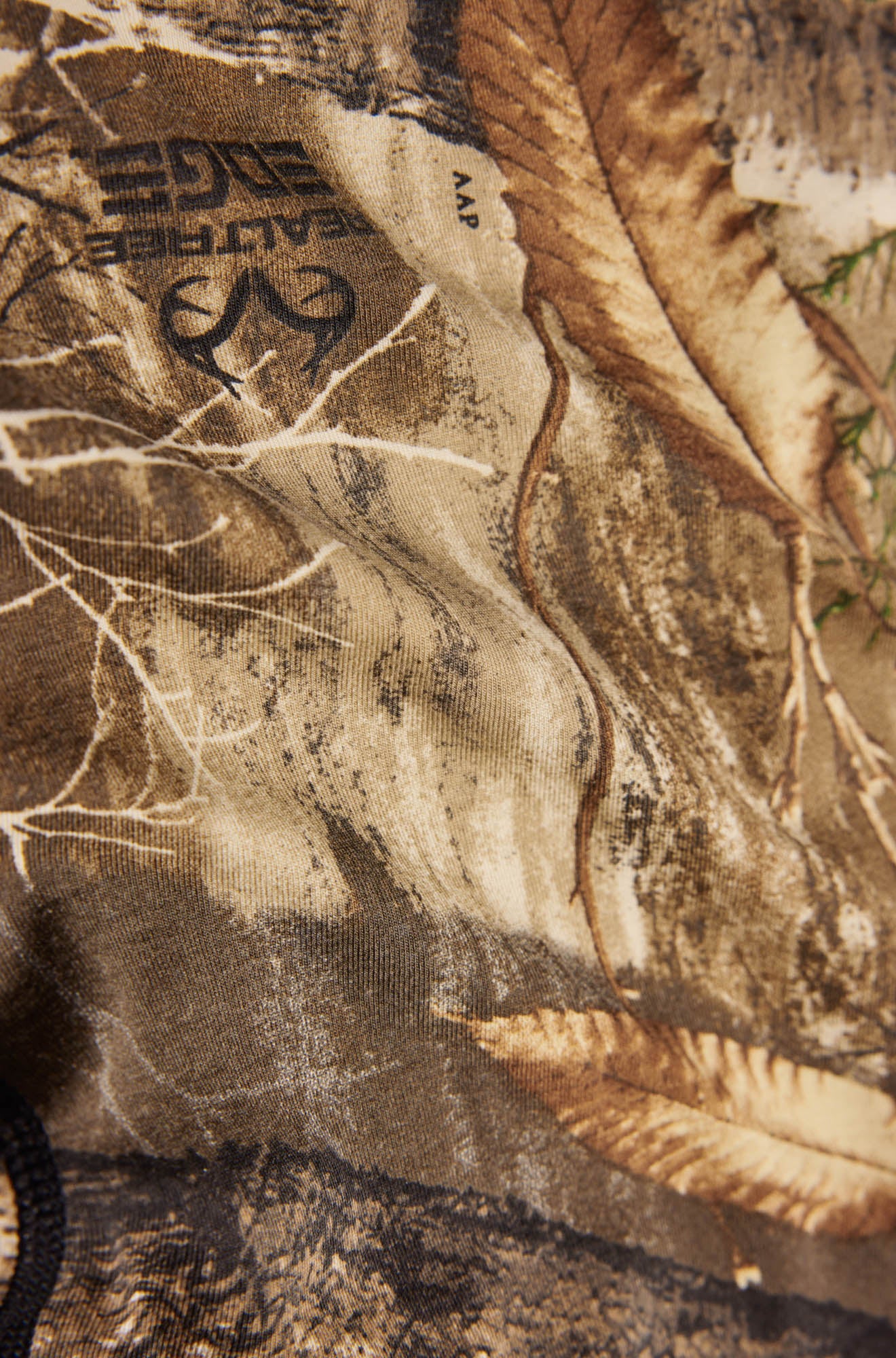 Détail rapproché du tissu camouflage brun en sous-vêtement avec marques Realtree, branches et feuilles pour homme par Saxx