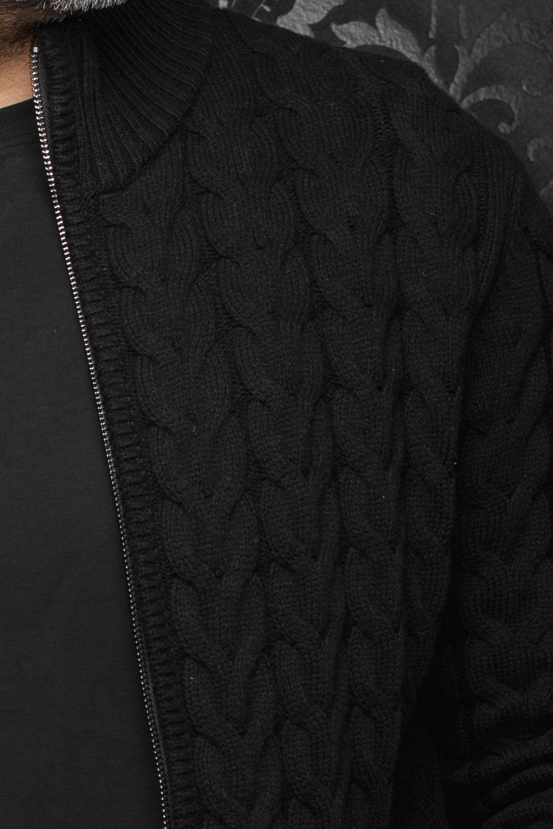Au Noir men's black cable-knit merino jacket shoulder and front zipper edge showing raised texture, close-up
